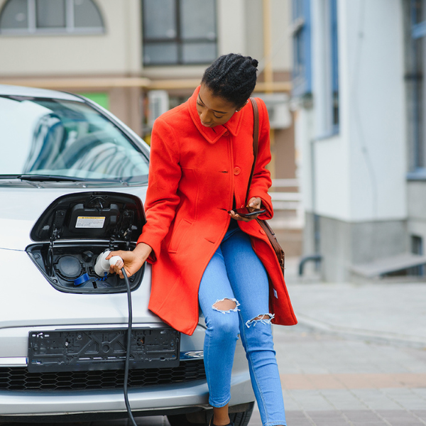 Women in red coat plugging in an EV charger
