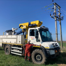 Adrian Farmer, Overhead Craft Technician standing next to a Unimog and overhead power line.