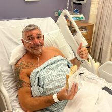Andy Emmott in hospital with a sandwich, giving a thumbs up