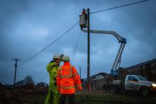 Two NPg colleagues discussing a repair to a line being completed in the background