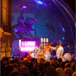 People in Durham City next to an illuminated snow globe